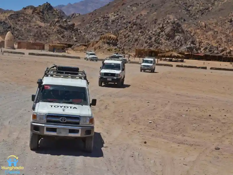 قافلة سيارات الجيب تنطلق بين الجبال الصحراوية الشاهقة